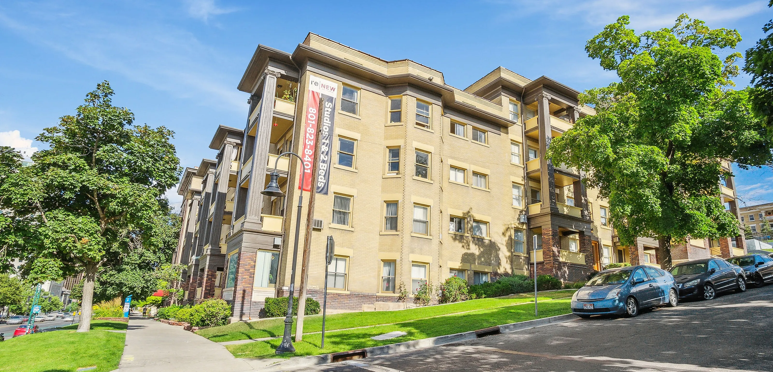 Charming apartment building with lush greenery, offering studio to 2-bedroom units in a vibrant neighborhood.