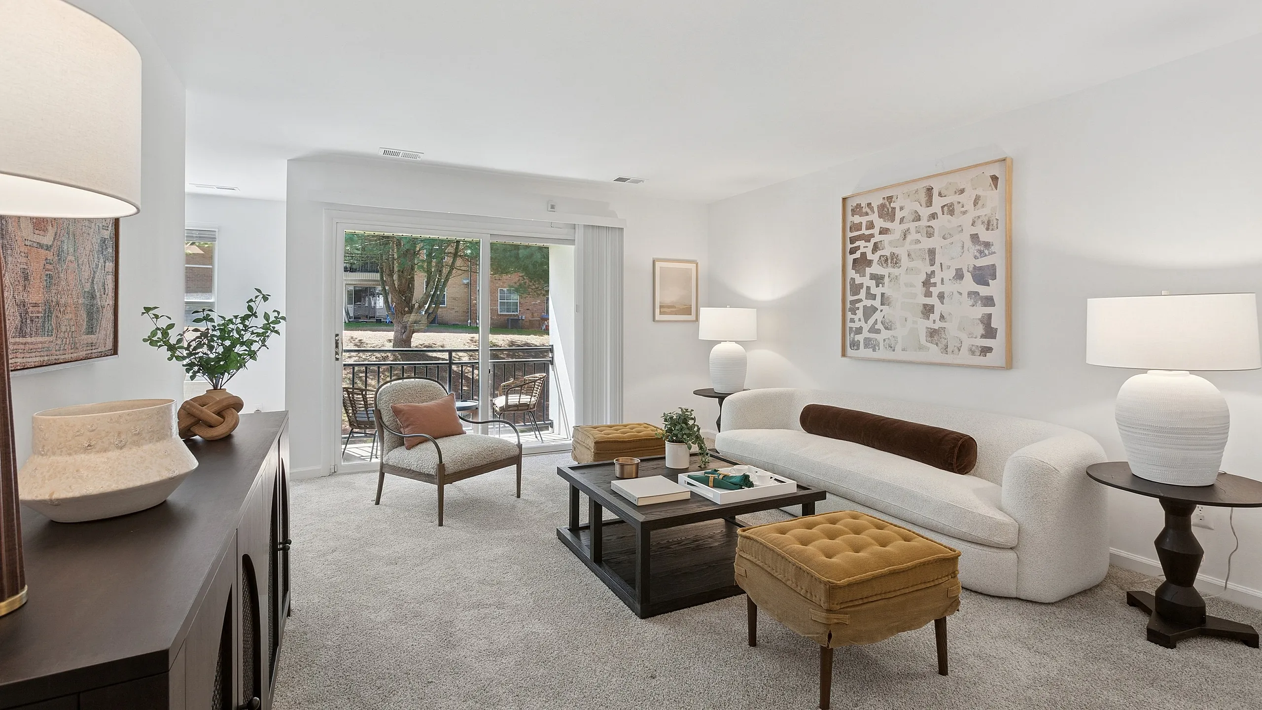 Chic and airy living room with elegant modern decor, featuring a plush white sofa, stylish coffee table, and vibrant natural light from sliding glass doors leading to an inviting balcony view.