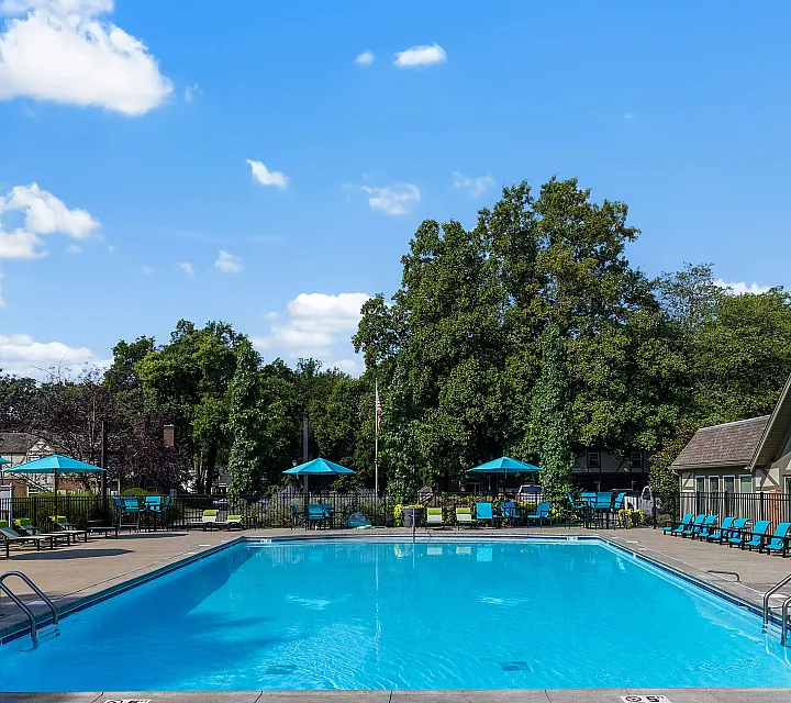 Inviting outdoor swimming pool area with vibrant turquoise umbrellas and lush greenery, perfect for relaxation and leisure.