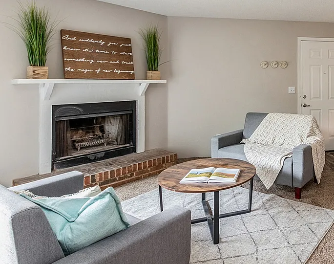 Cozy living room with modern decor, featuring a warm fireplace, stylish furniture, and an inviting open kitchen with bar seating.