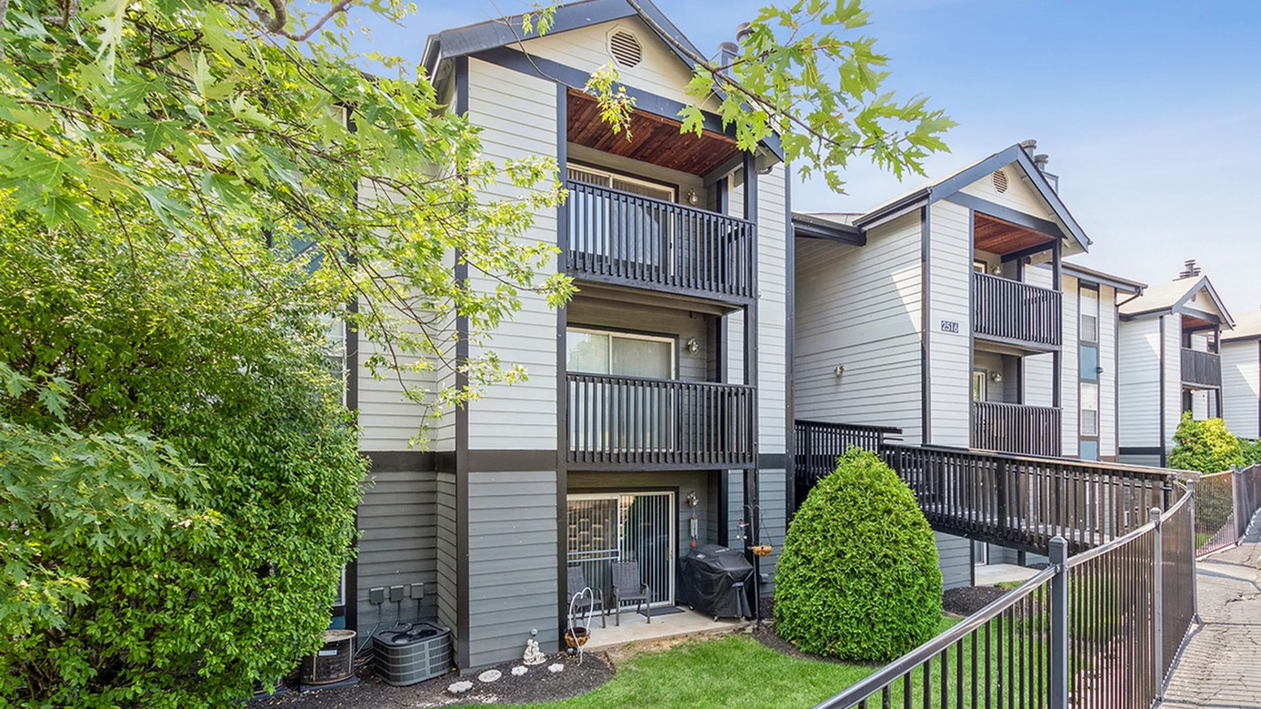 Charming multi-level apartment building with private balconies, surrounded by lush greenery and pristine landscaping.