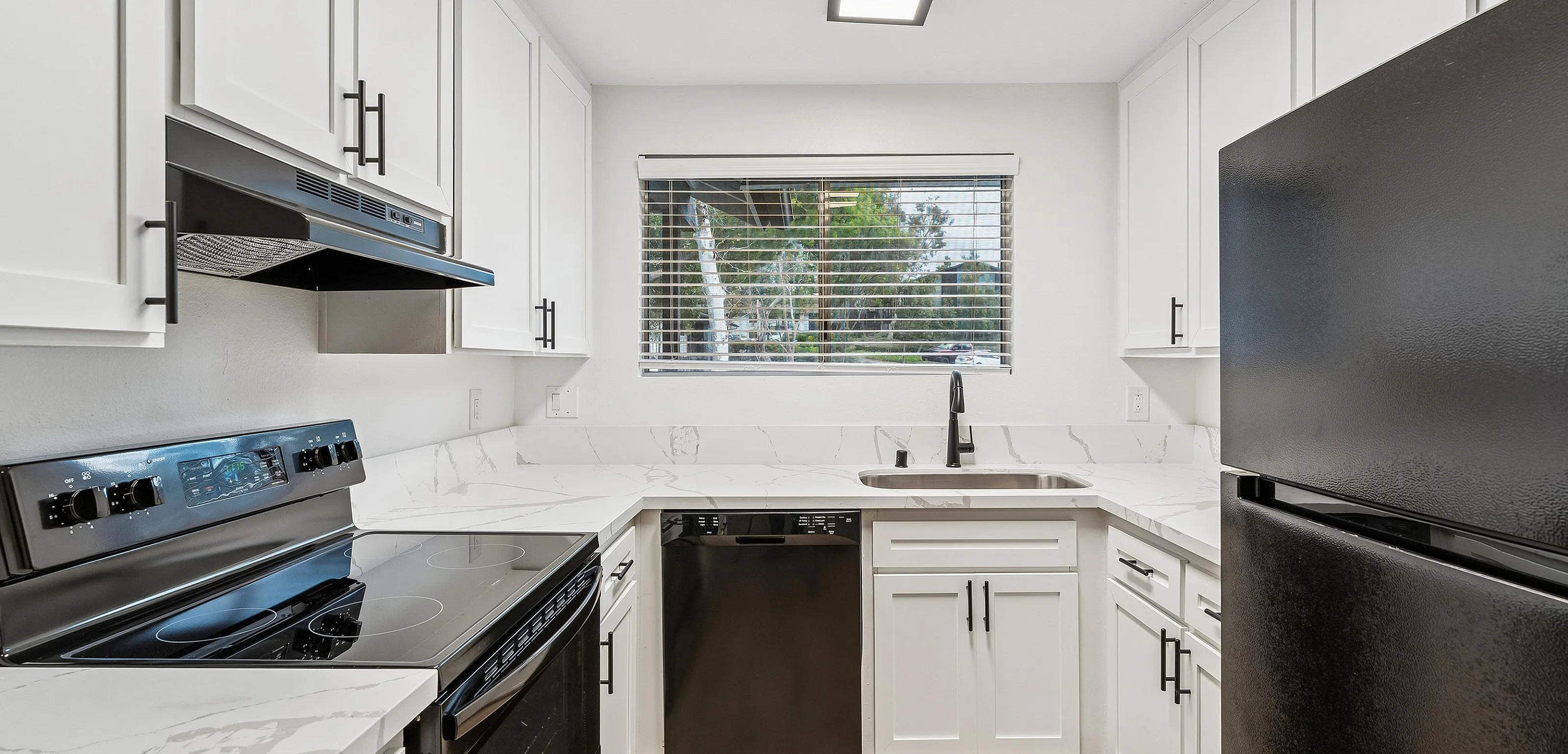 Modern kitchen with sleek black appliances, elegant white cabinetry, and stylish marble countertops.