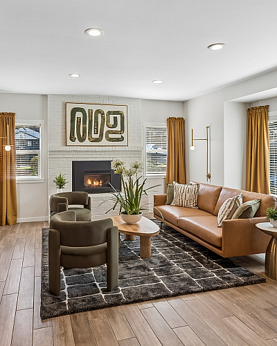 Inviting open-concept living room with modern kitchen, featuring a cozy fireplace, stylish decor, and abundant natural light through large windows.