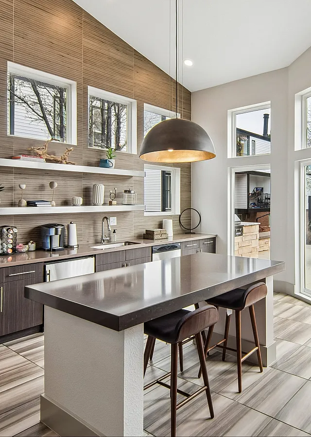Modern kitchen with sleek countertops, large windows, and elegant shelving, offering natural light and a chic design.