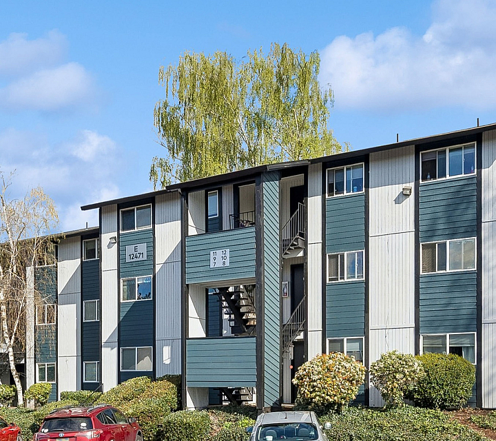 Charming apartment building surrounded by lush greenery and ample parking spaces, offering a peaceful residential atmosphere.