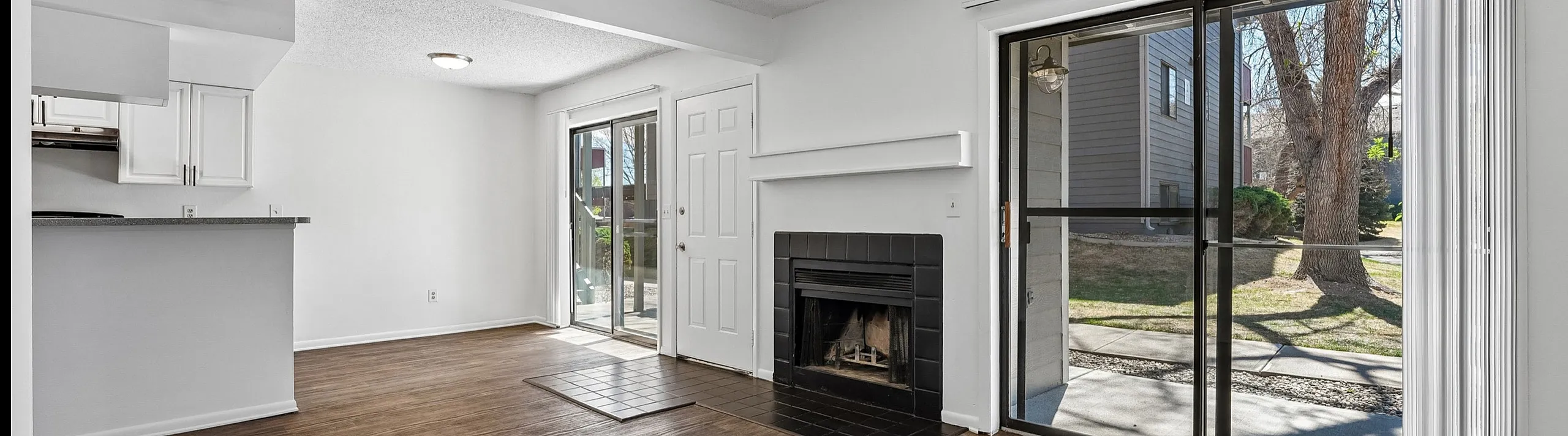 Bright and airy living space featuring hardwood floors, a cozy fireplace, and expansive sliding glass doors opening to a private outdoor area.