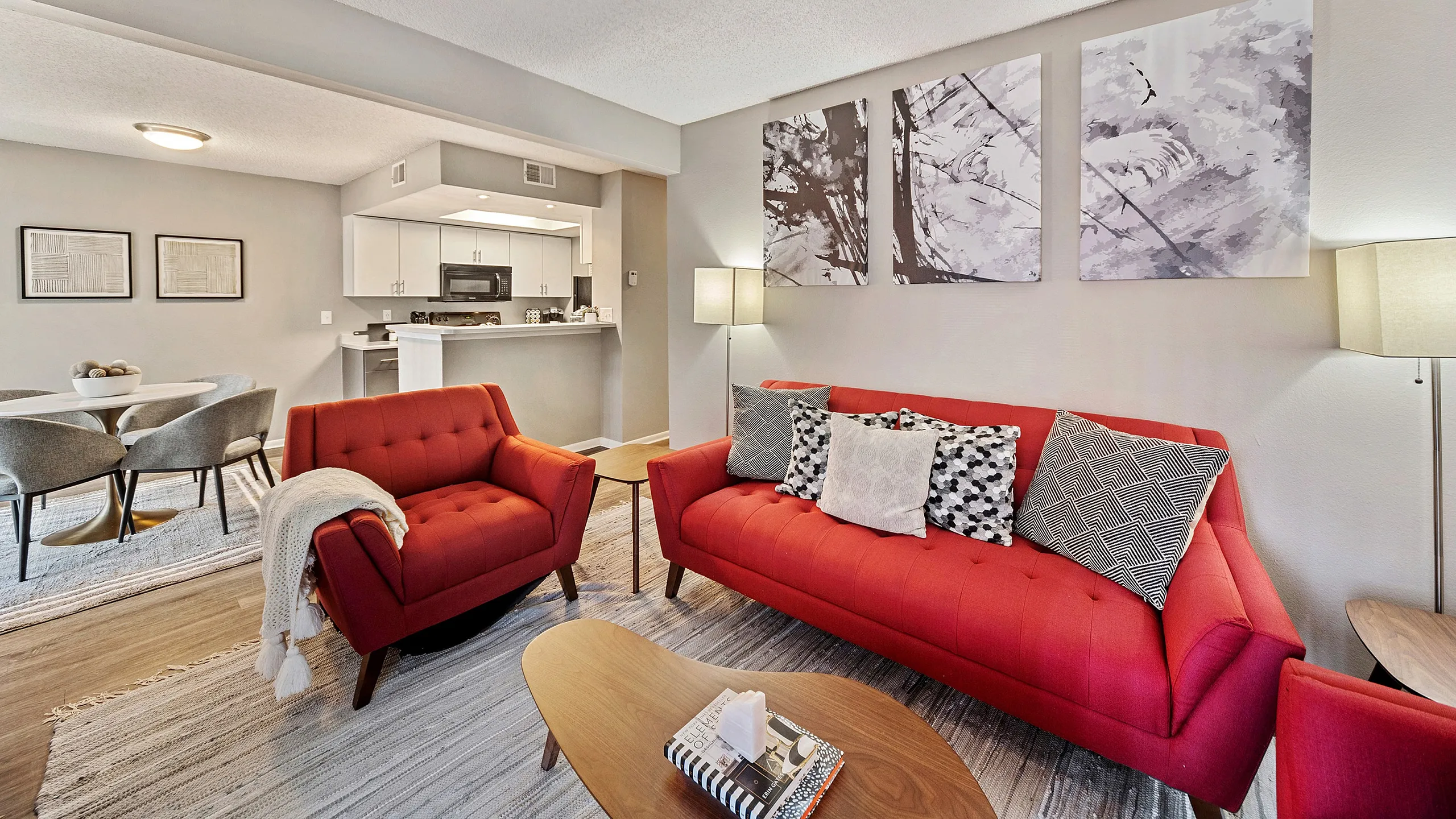 Inviting living room with vibrant red sofas, modern decor, and an open concept leading to a contemporary kitchen.