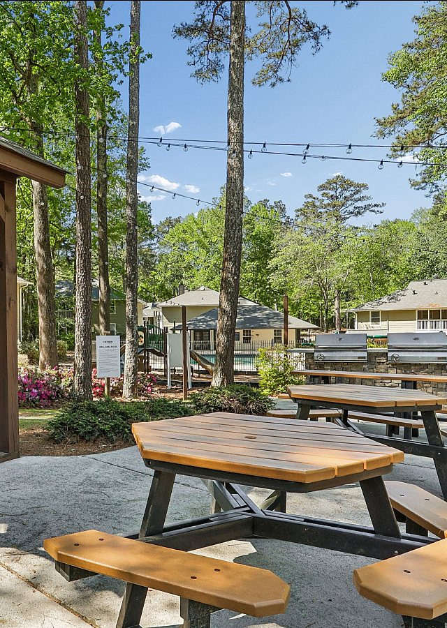 Charming outdoor area featuring a stylish wooden gazebo, picnic tables, and vibrant garden scenery, perfect for relaxation and gatherings.