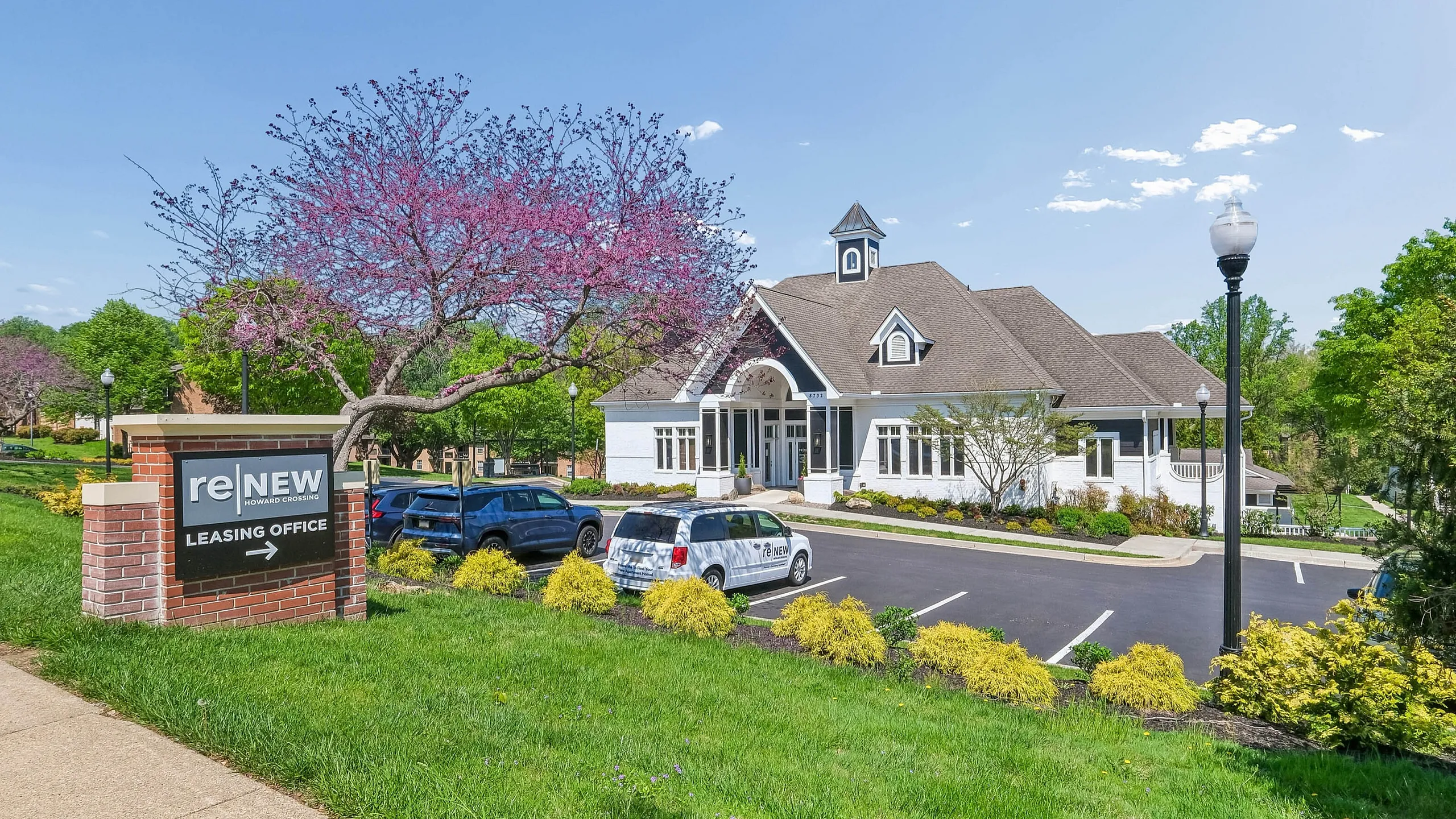 Charming leasing office surrounded by lush greenery and vibrant pink blossoms, showcasing an inviting atmosphere for prospective residents.