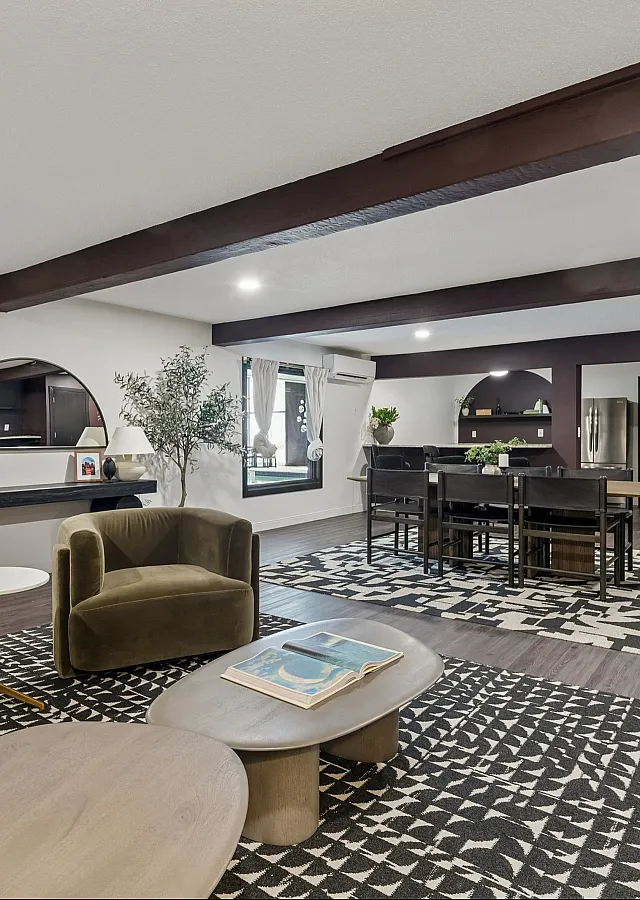 Sophisticated living area showcasing modern d&eacute;cor, earthy-toned armchairs, and an elegant dining setup under warm ambient lighting.