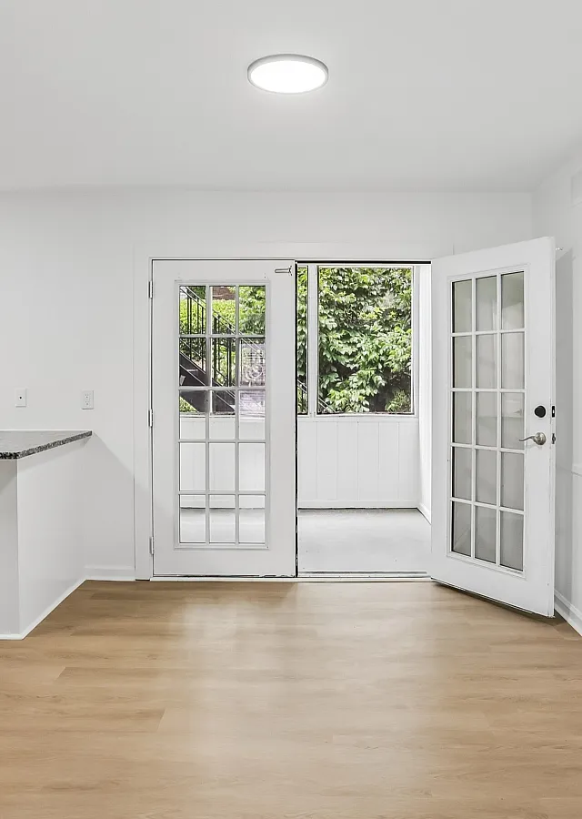 Bright and airy living space with elegant French doors leading to a lush garden view, featuring stylish hardwood floors and modern finishes.