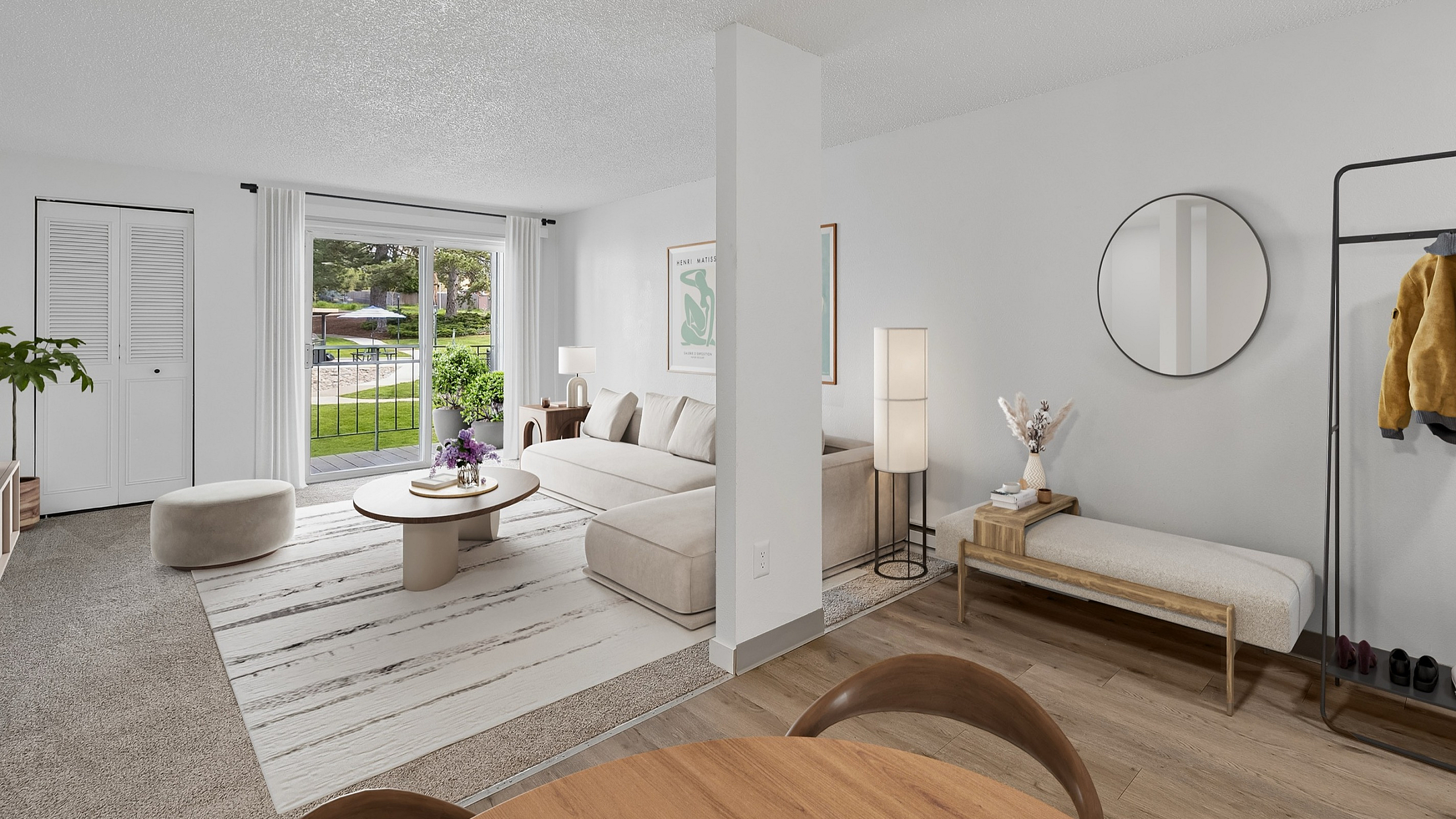 Bright and inviting living room with elegant decor, featuring a cozy beige couch, sleek coffee table, modern ceiling fan, and large sliding windows opening to a lush garden view.