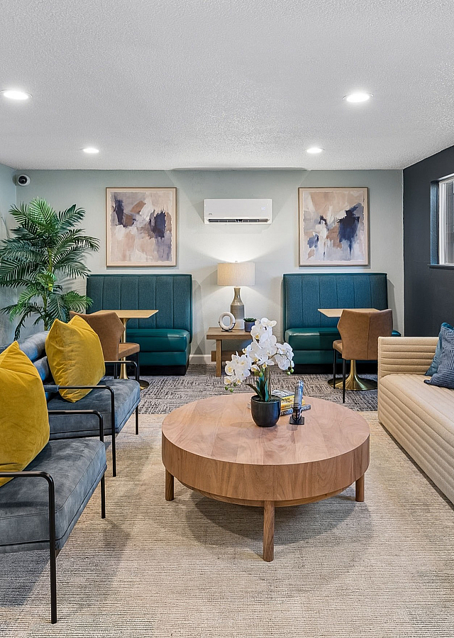 Inviting lounge area featuring modern furniture with vibrant cushions, stylish artwork, and large windows offering garden views.