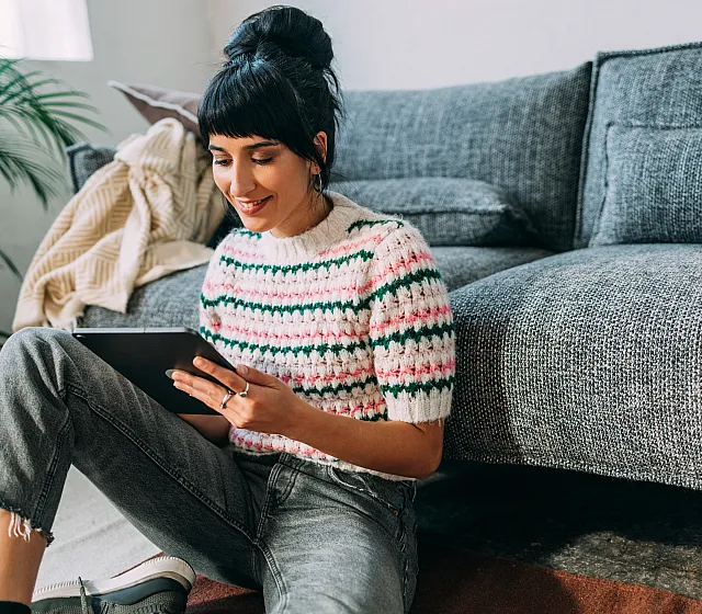 Cozy living space with a cheerful person enjoying leisure time on a comfortable gray sofa, surrounded by natural decor and soft lighting.