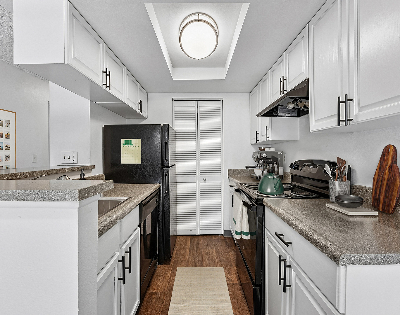 Modern kitchen featuring sleek white cabinetry, elegant countertops, and contemporary appliances with a cozy wooden floor finish.