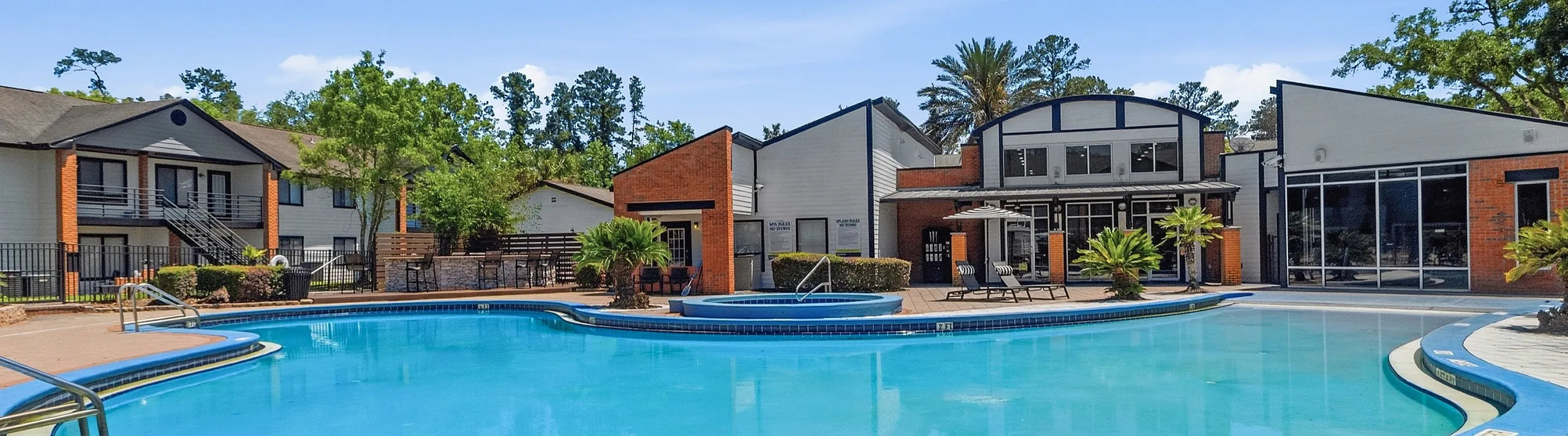 Luxurious apartment complex with a stunning outdoor pool, surrounded by modern architecture and lush greenery.