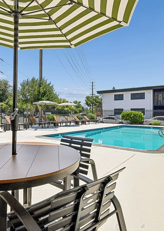 Inviting poolside area with stylish outdoor seating and large umbrellas, providing a perfect spot for relaxation in a serene environment.