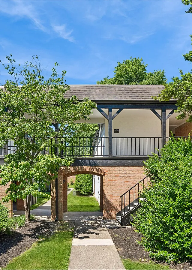 Charming apartment exterior with elegant brickwork and lush greenery under a clear blue sky.