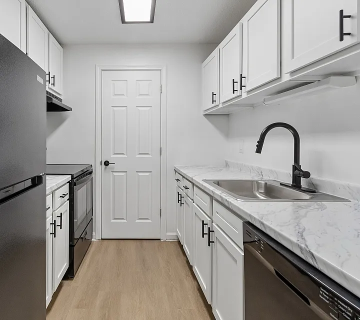Modern kitchen with sleek black appliances, elegant white cabinetry, and stylish marble countertops.
