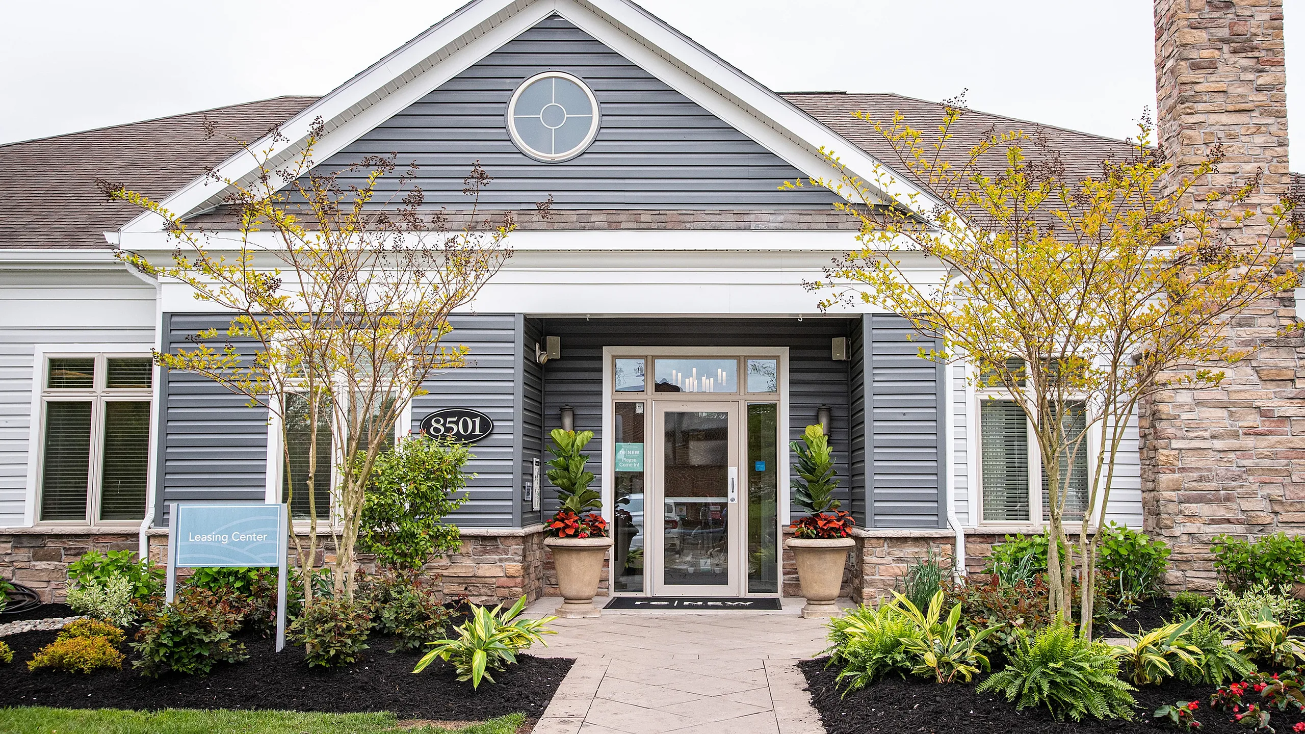 Charming leasing center with elegant stone facade, manicured landscaping, and inviting entrance.