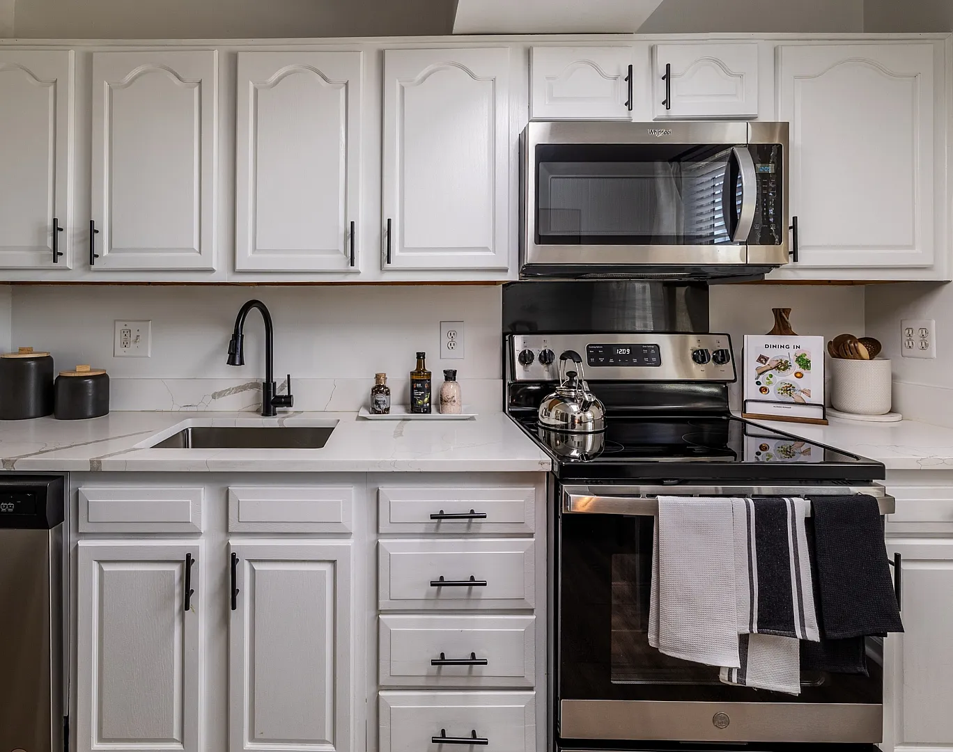 Modern kitchen with sleek stainless steel appliances, elegant white cabinetry, and a polished marble countertop.