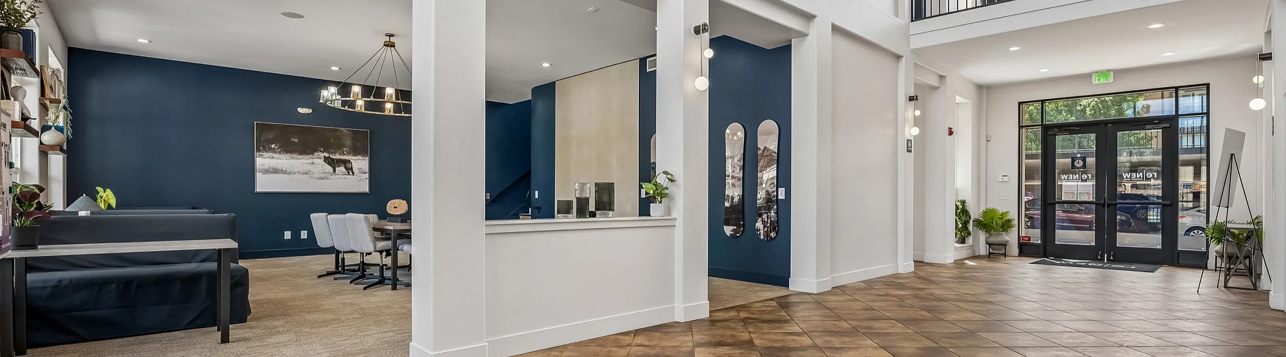 Elegant apartment lobby with high ceilings, modern chandelier, and stylish decor, featuring a spacious seating area and large windows for natural light.
