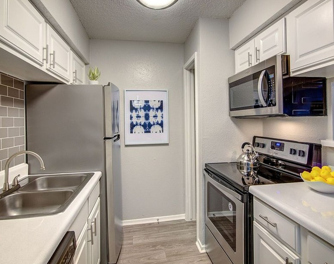 Modern kitchen with stainless steel appliances, sleek white cabinets, and elegant tile backsplash, showcasing contemporary design and functionality.