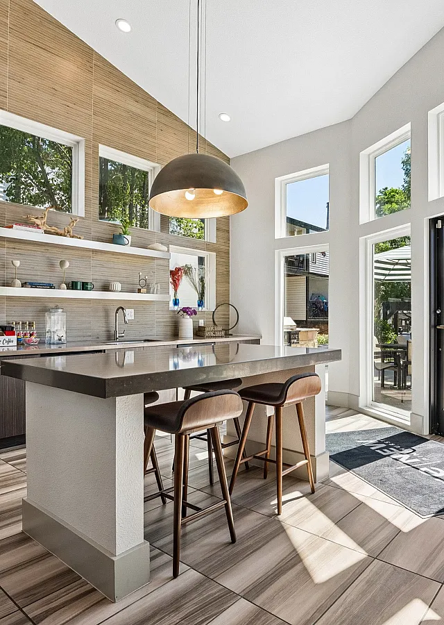 Bright and modern kitchen with sleek countertops, stylish open shelving, and large windows overlooking a sunlit patio.