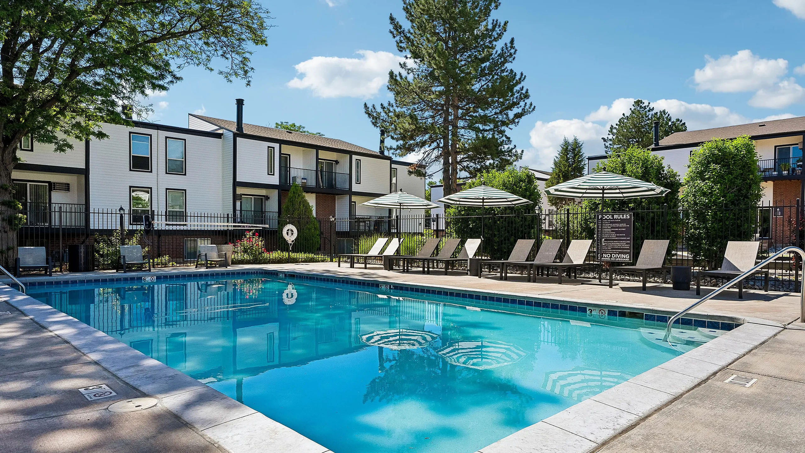 Inviting outdoor pool area with modern lounge chairs and patio umbrellas, set in a serene residential community.