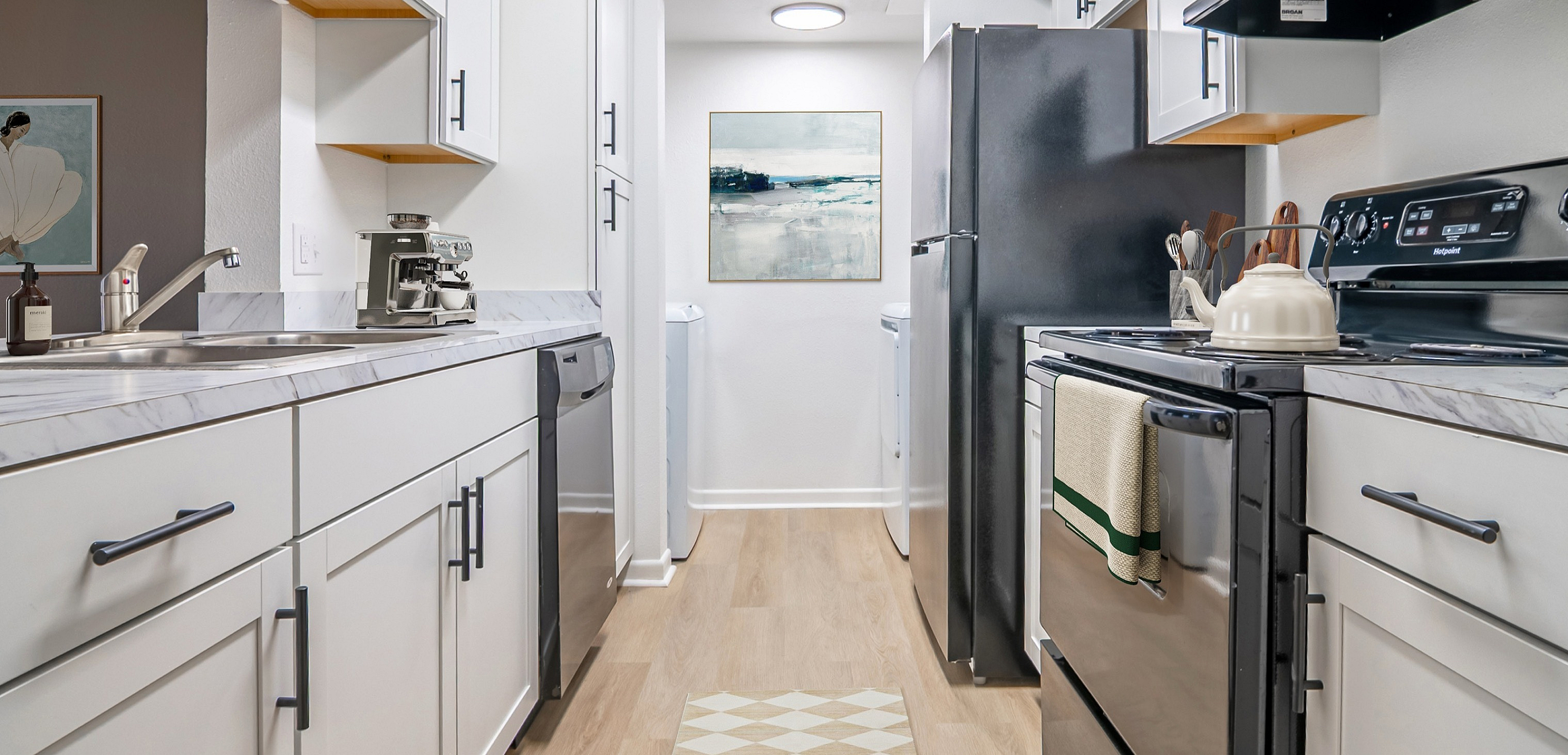 Modern kitchen with sleek white cabinets, stainless steel appliances, and elegant wood flooring.
