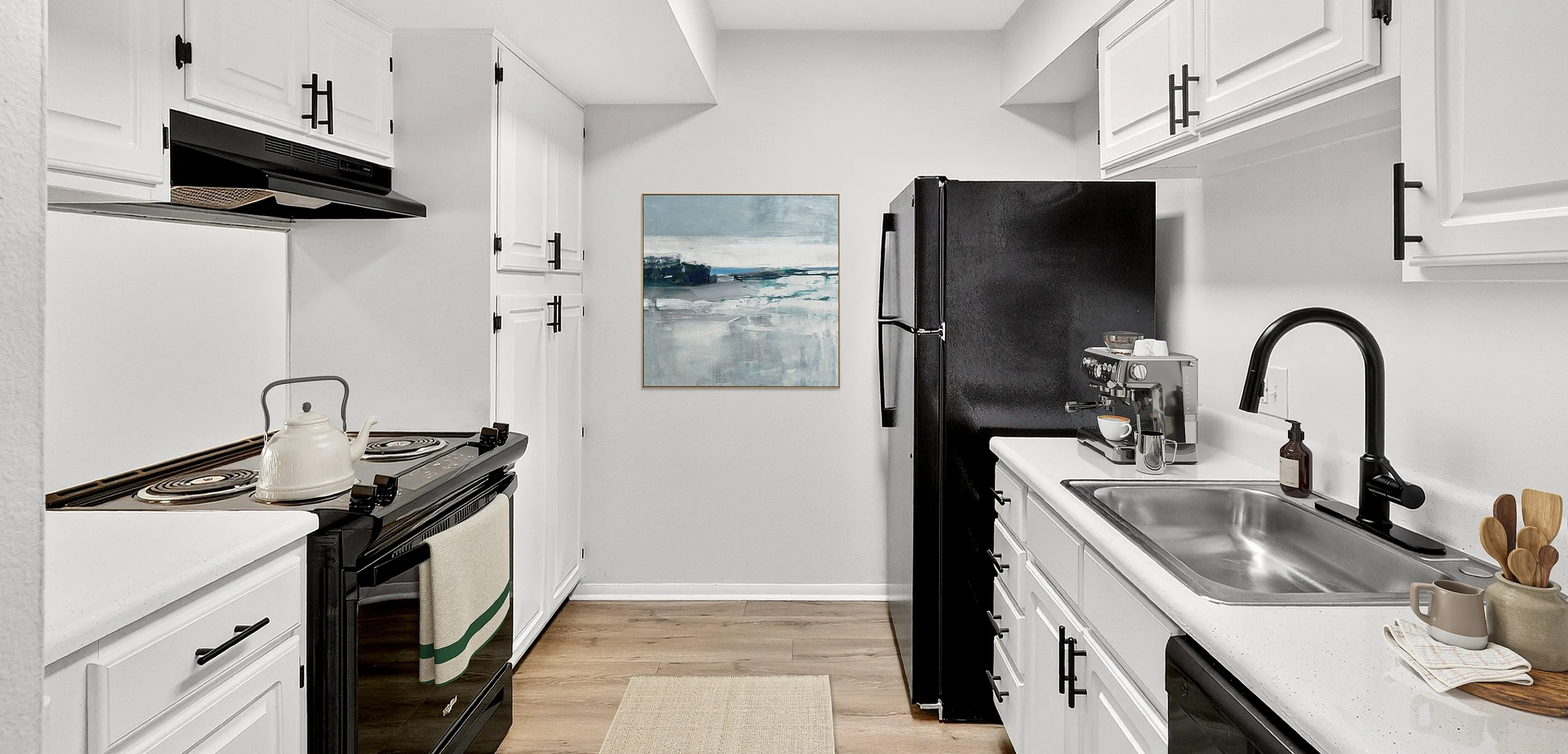 Modern kitchen with sleek black and white design, featuring ample cabinetry, a stylish cooktop, and a contemporary refrigerator.
