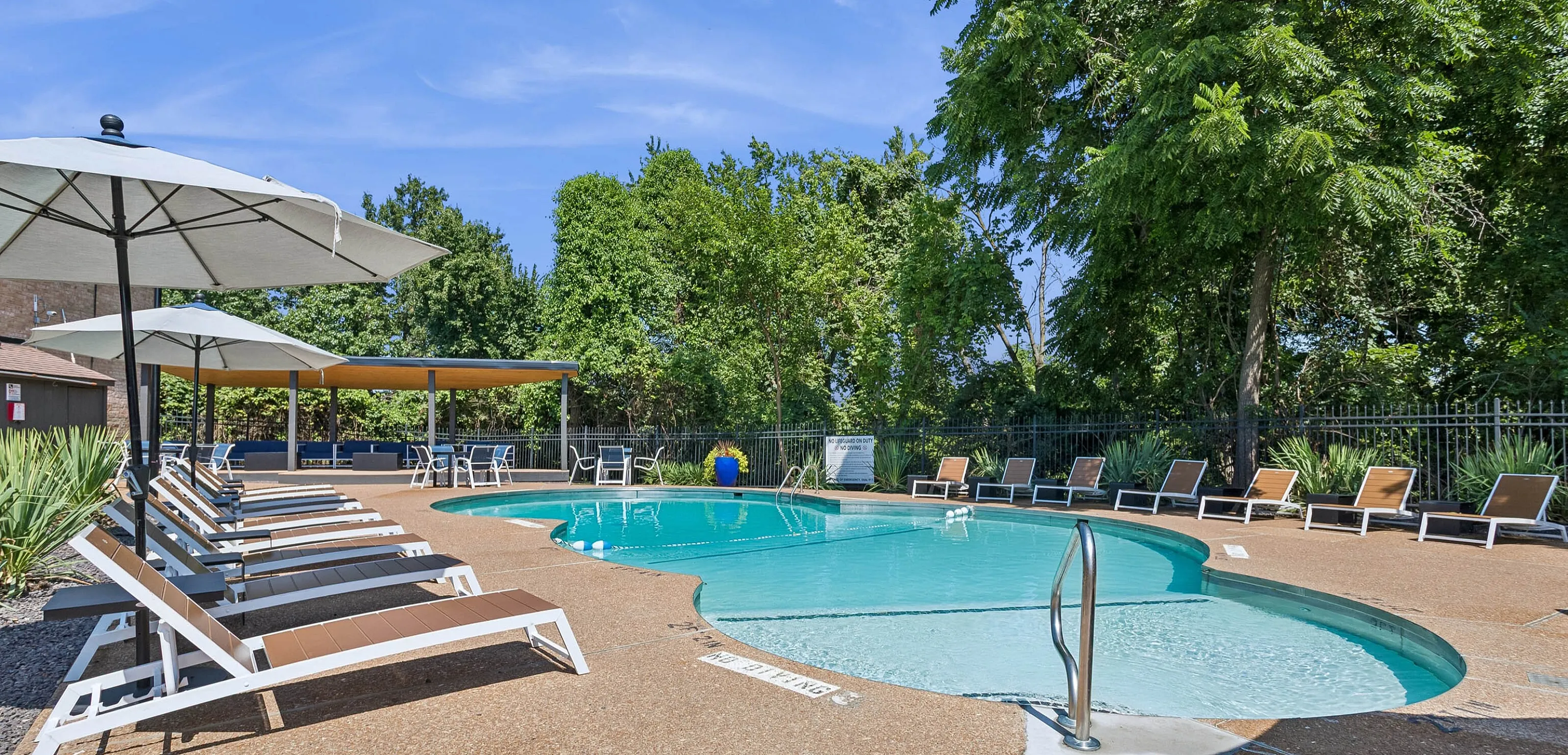 Inviting outdoor pool area with comfortable lounge chairs, umbrellas, and lush greenery, perfect for relaxation and leisure.