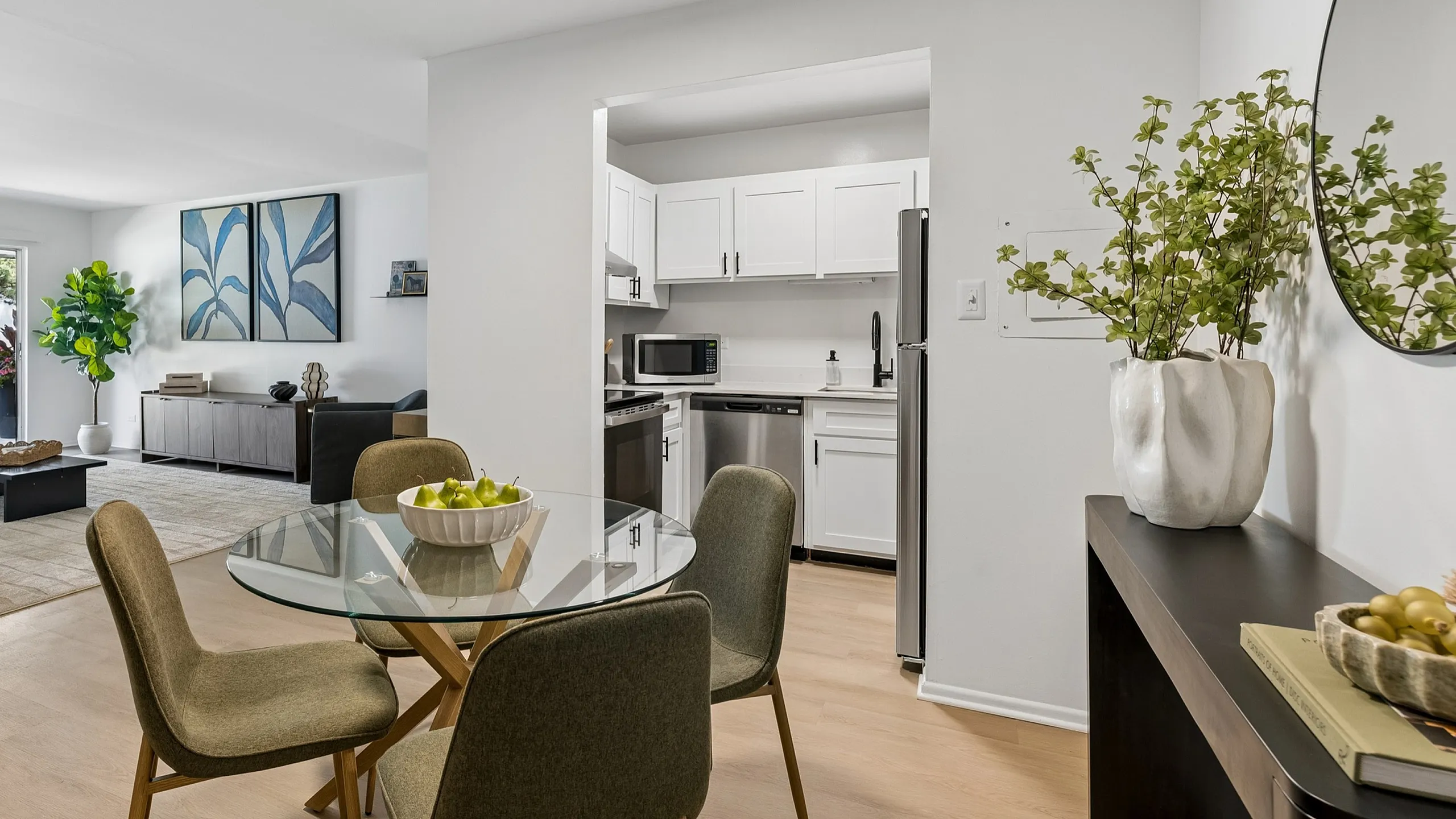 Contemporary open-concept apartment featuring a bright kitchen, elegant dining area with a glass table, and a cozy living room with stylish decor.