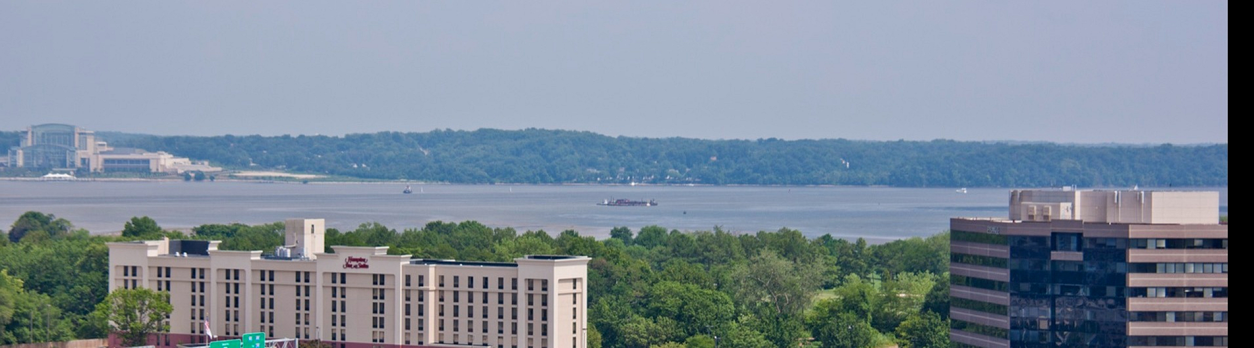 Scenic panoramic view of urban landscape featuring modern buildings and lush greenery with a serene waterfront backdrop.