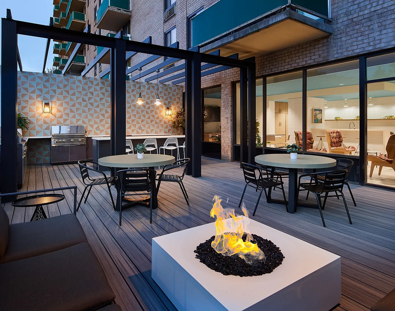 Modern outdoor apartment terrace featuring cozy seating, a stylish fire pit, and elegant geometric wall design.