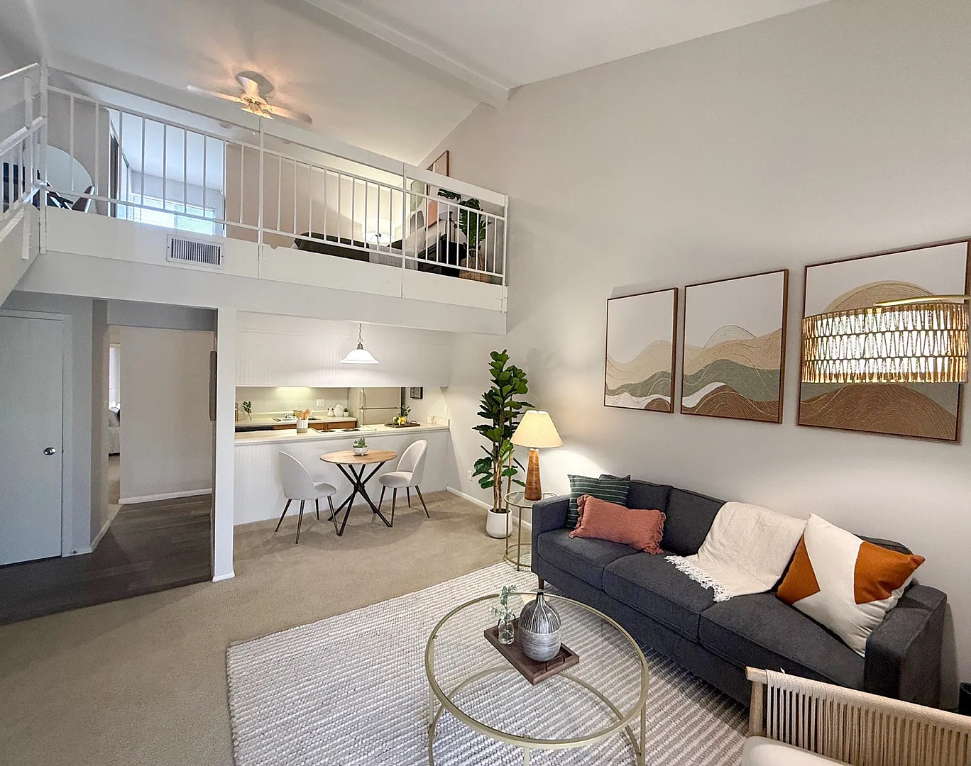 Modern living space with a loft bedroom, featuring a cozy sitting area, elegant decor, and a quaint dining nook.