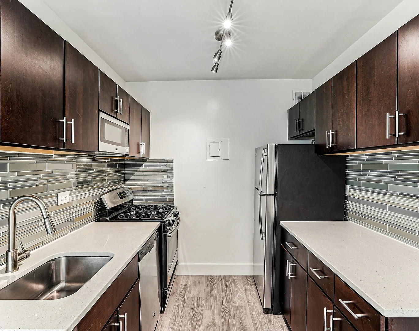 Modern kitchen with sleek dark wood cabinets, stainless steel appliances, and elegant tile backsplash.