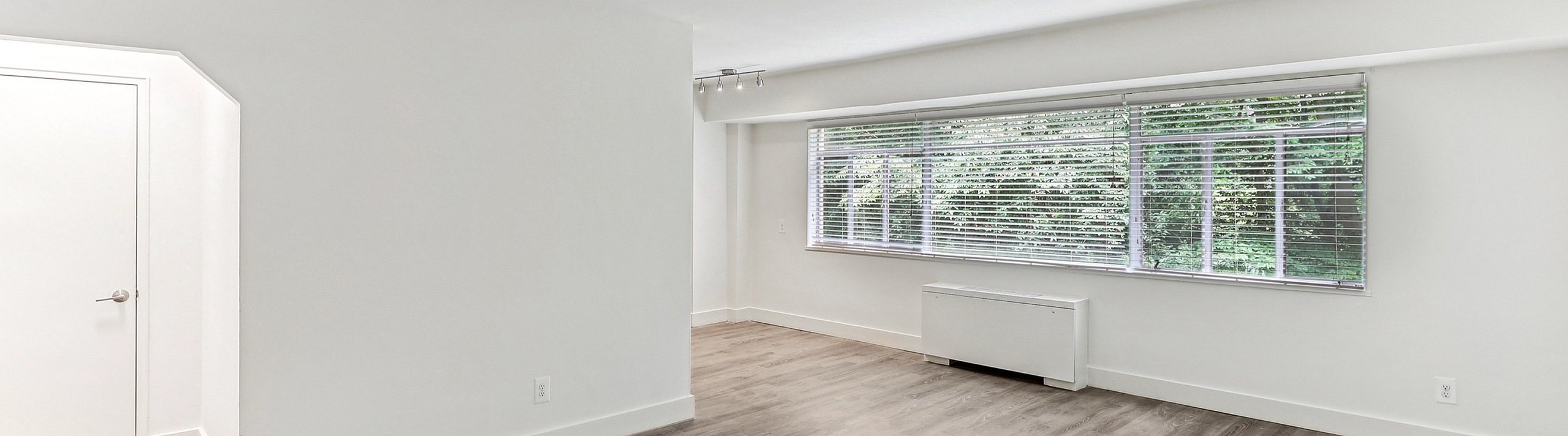 Bright and airy living area with elegant wood flooring and expansive window views, perfect for modern living.