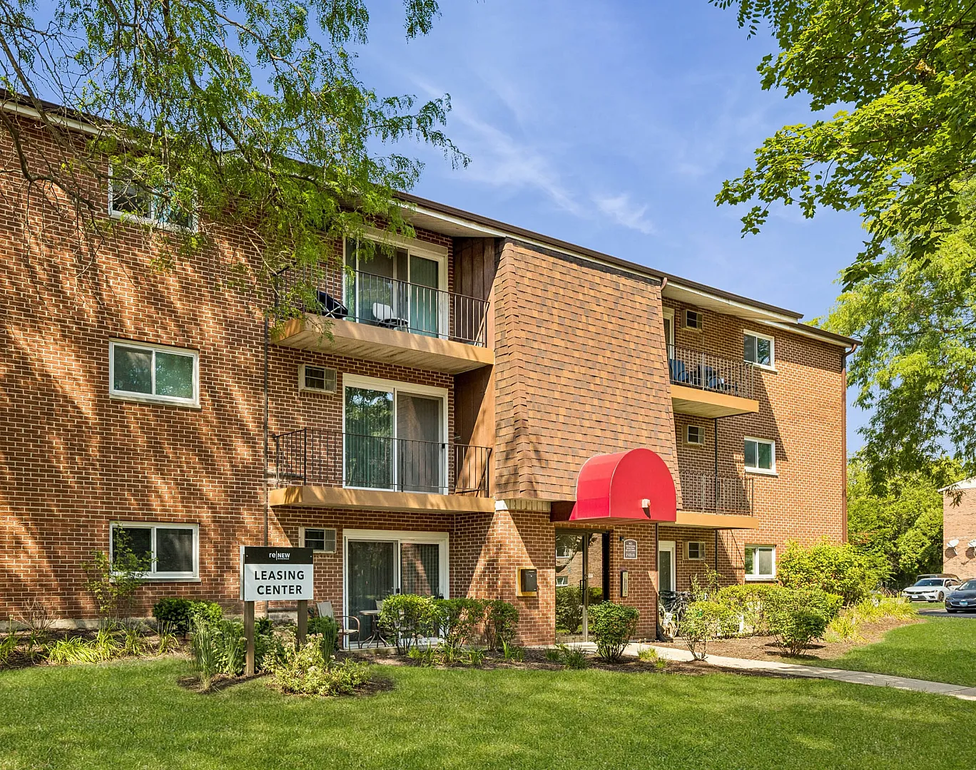 Charming red-brick apartment building with private balconies and lush green surroundings.