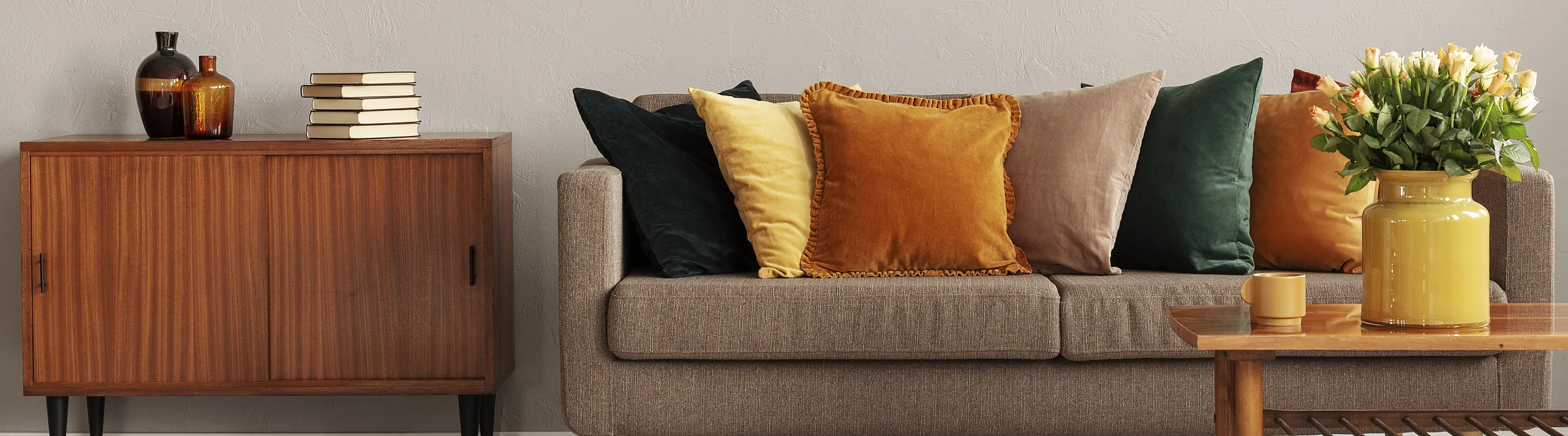 Chic modern living room with a cozy brown sofa adorned with colorful cushions, a stylish wooden sideboard, vibrant art, and a warm atmosphere.