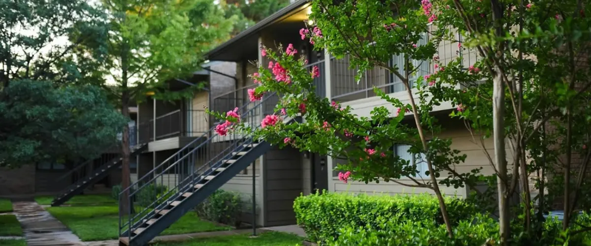 Community with lush green lawns and tall trees.