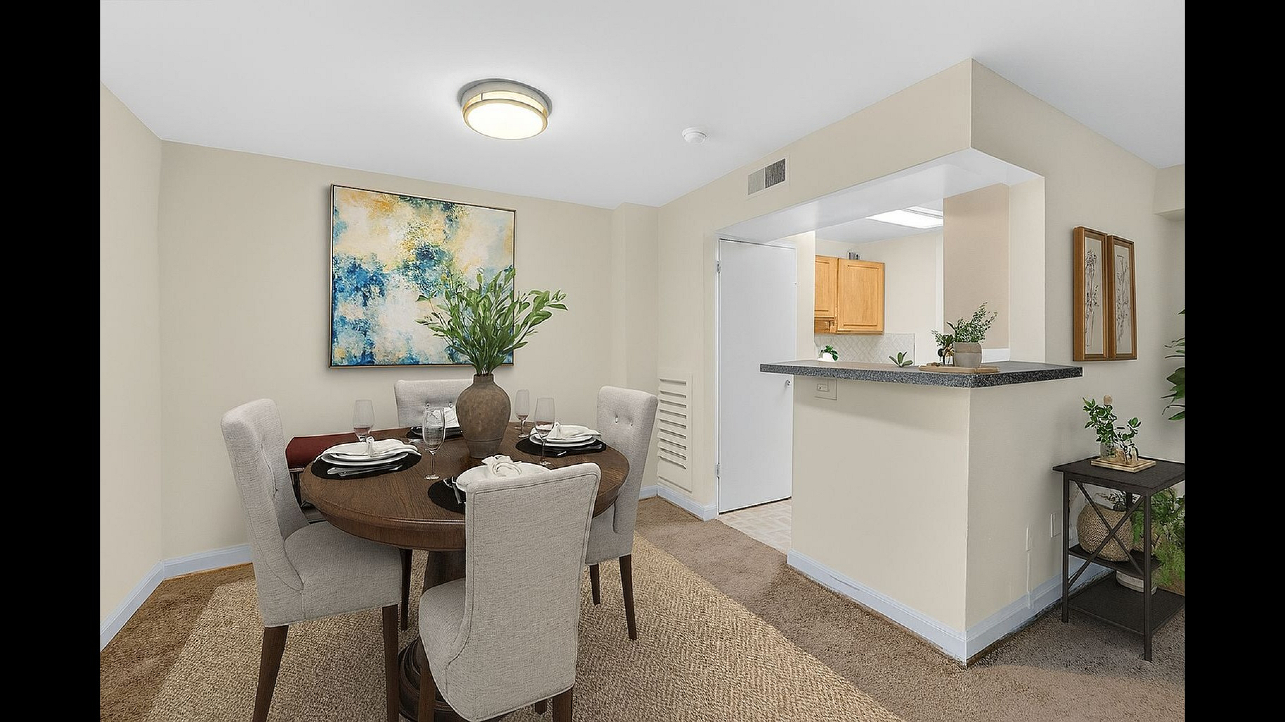 Elegant dining area with cozy seating, decorative artwork, and open access to a bright modern kitchen showcasing contemporary design.