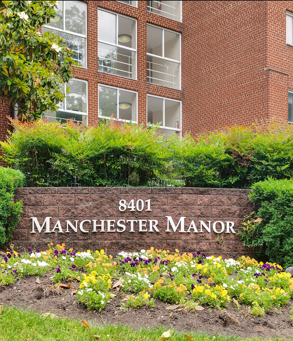 Charming entrance view of Manchester Manor with vibrant landscaping and stylish architectural design.