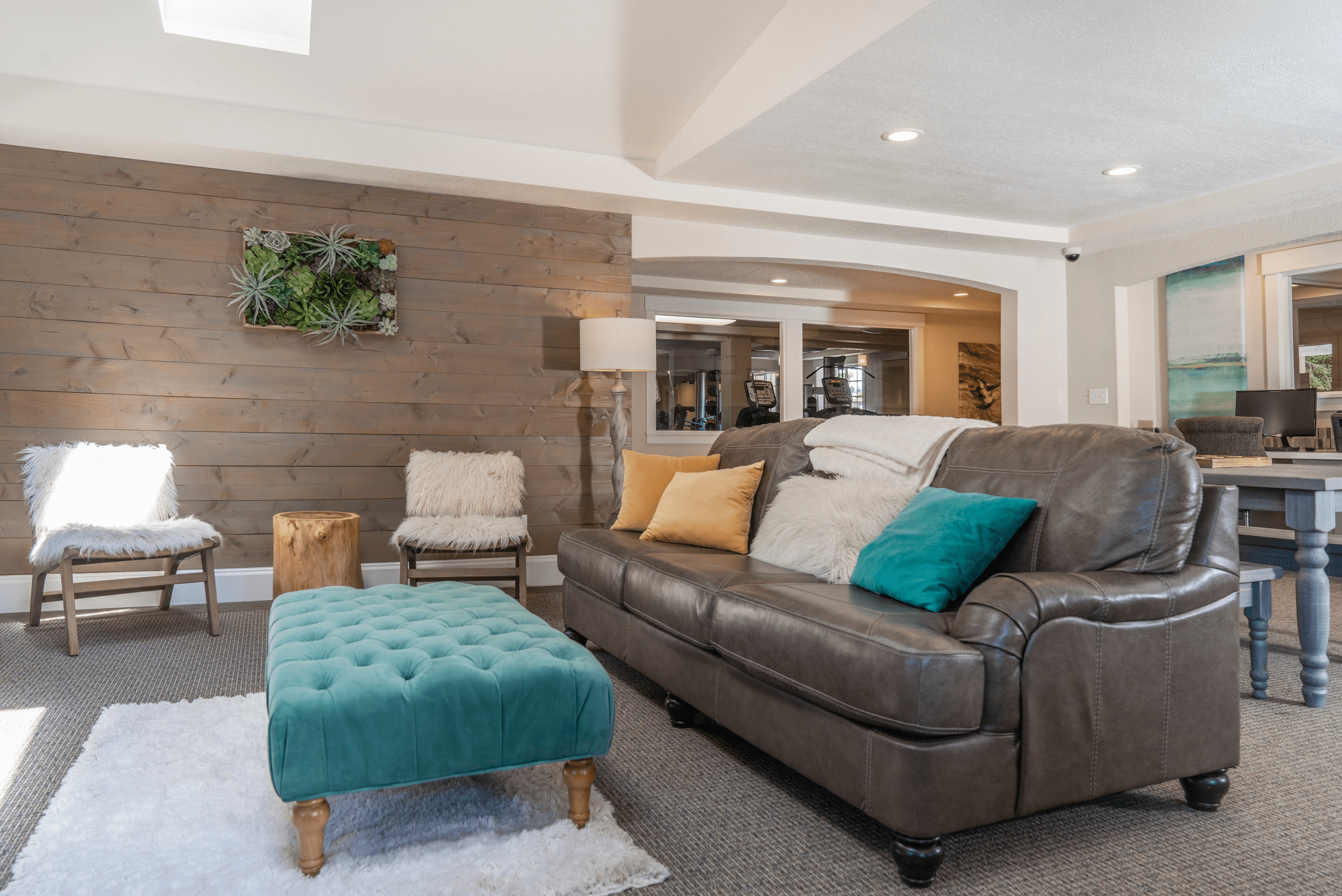 Inviting living room with a gray leather sofa, colorful throw pillows, wooden accent wall, and modern decor.