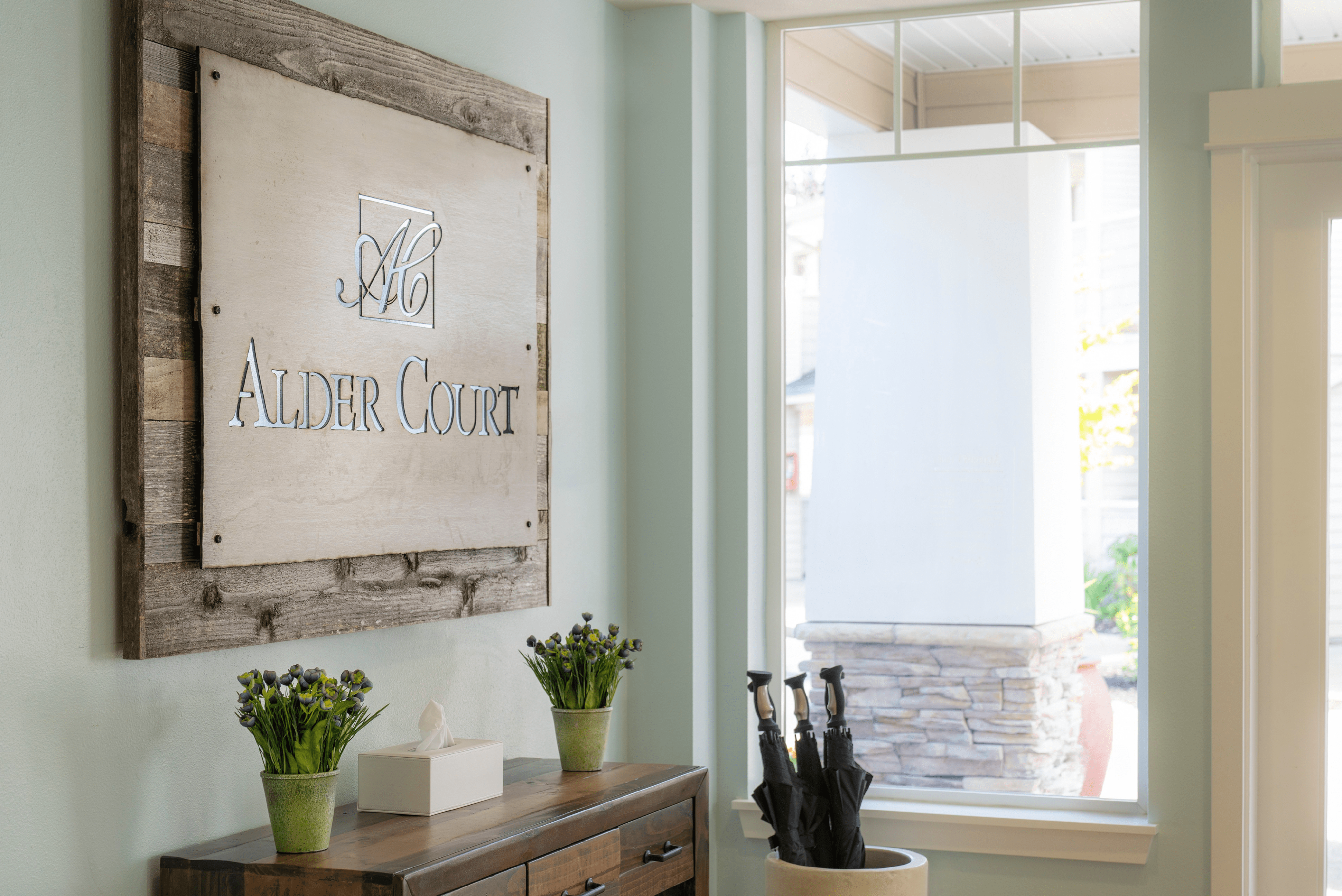 Inviting entrance of Alder Court with stylish wooden decor and natural light streaming in through large windows.
