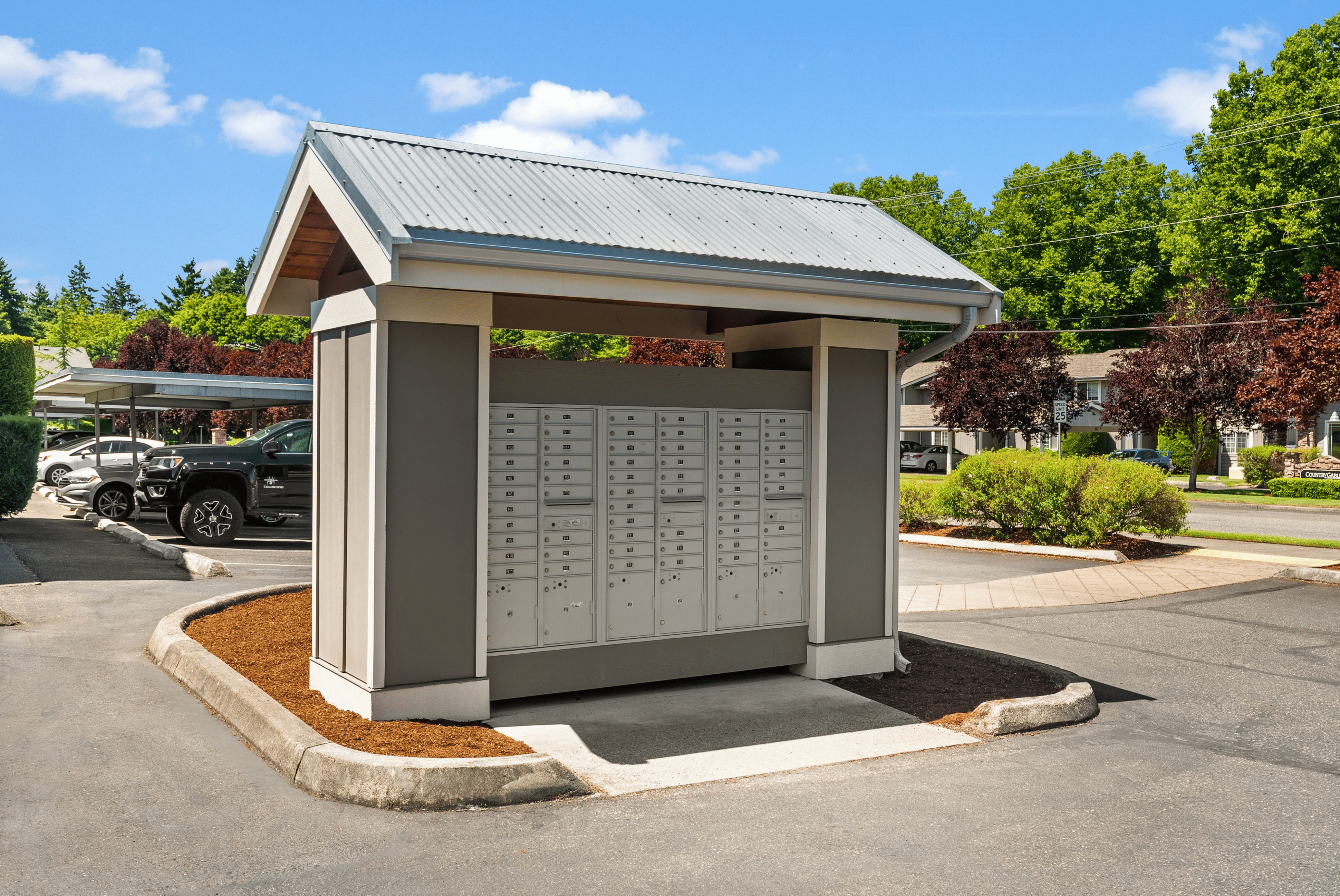 Charming outdoor mail kiosk with individual mailboxes nestled in a well-maintained community setting, surrounded by lush greenery and convenient parking.