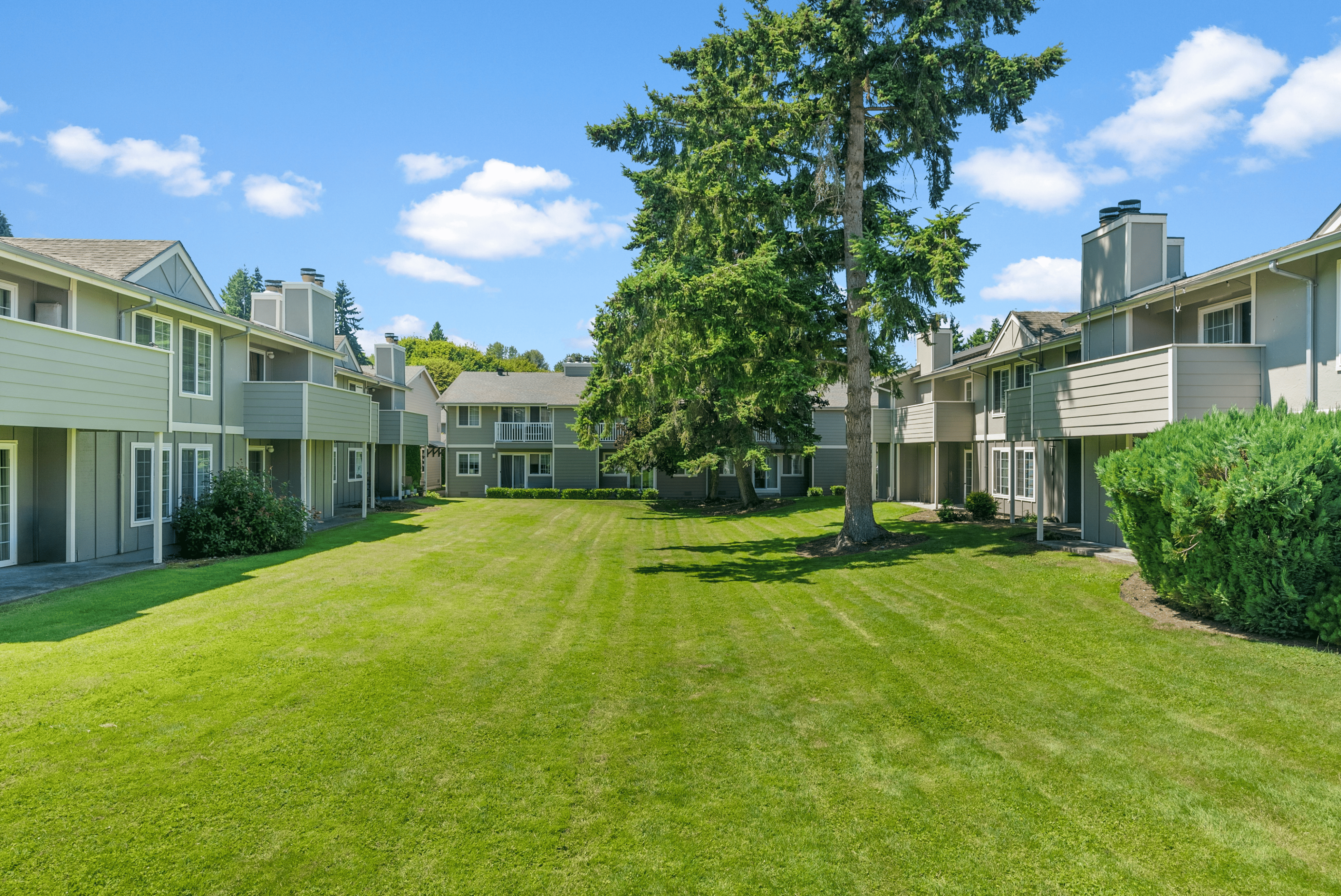 Charming apartment complex surrounded by lush greenery and vibrant gardens, offering serene living and ample outdoor space.