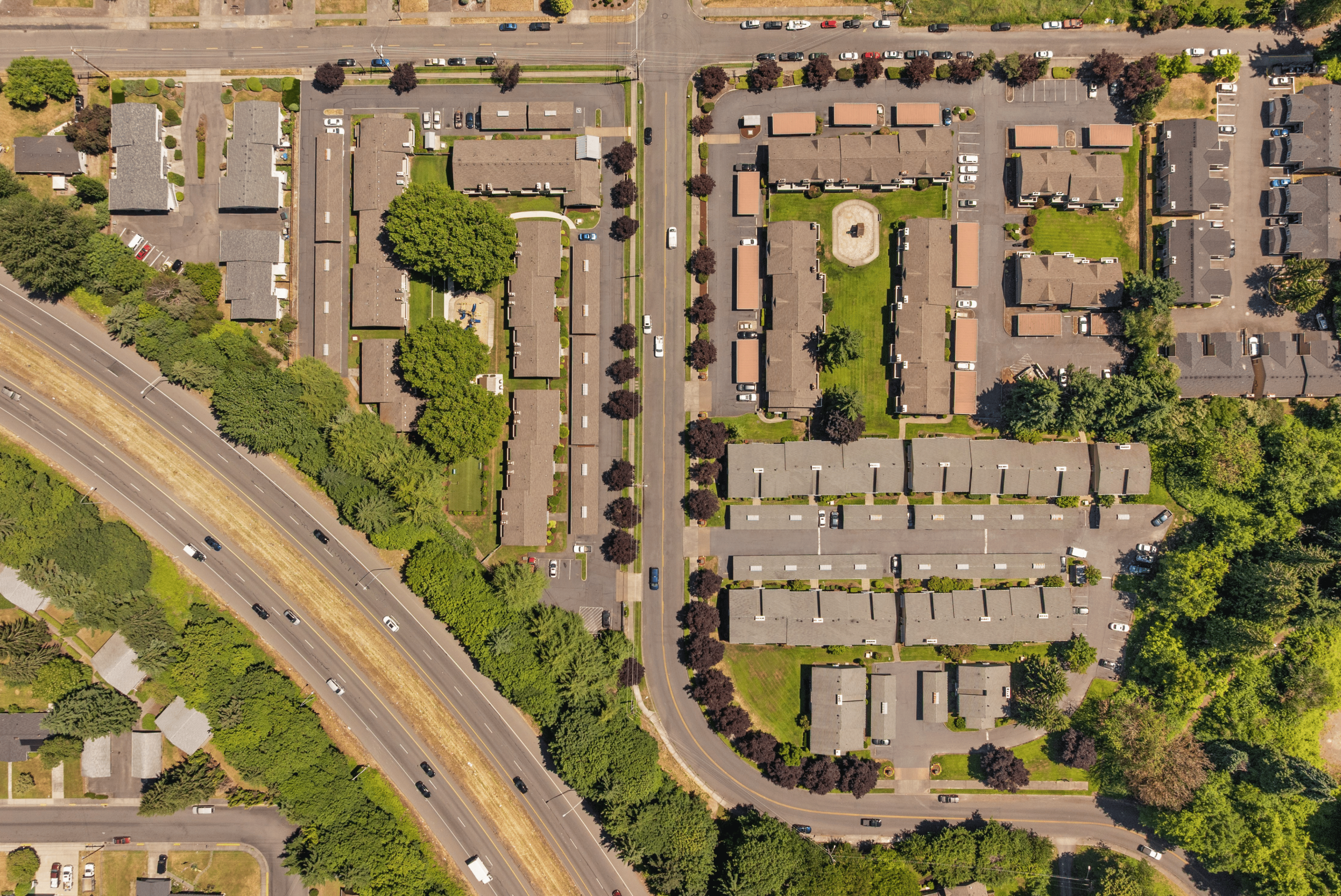 Bird's-eye view of a beautifully arranged apartment complex featuring lush greenery, spacious layouts, and convenient road access.