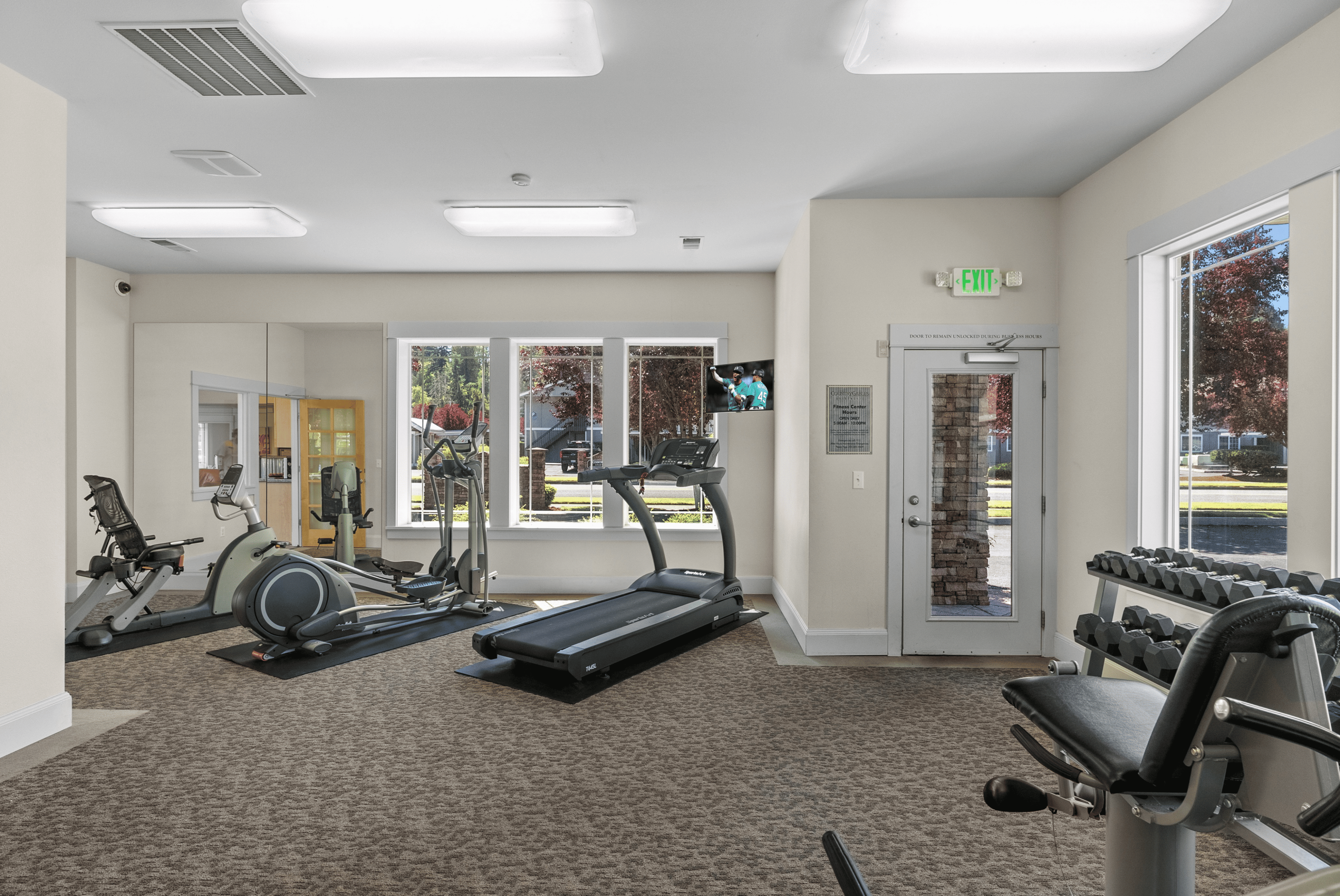 Modern fitness center with state-of-the-art equipment, featuring treadmills, weights, and stationary bikes, illuminated by natural light from large windows.