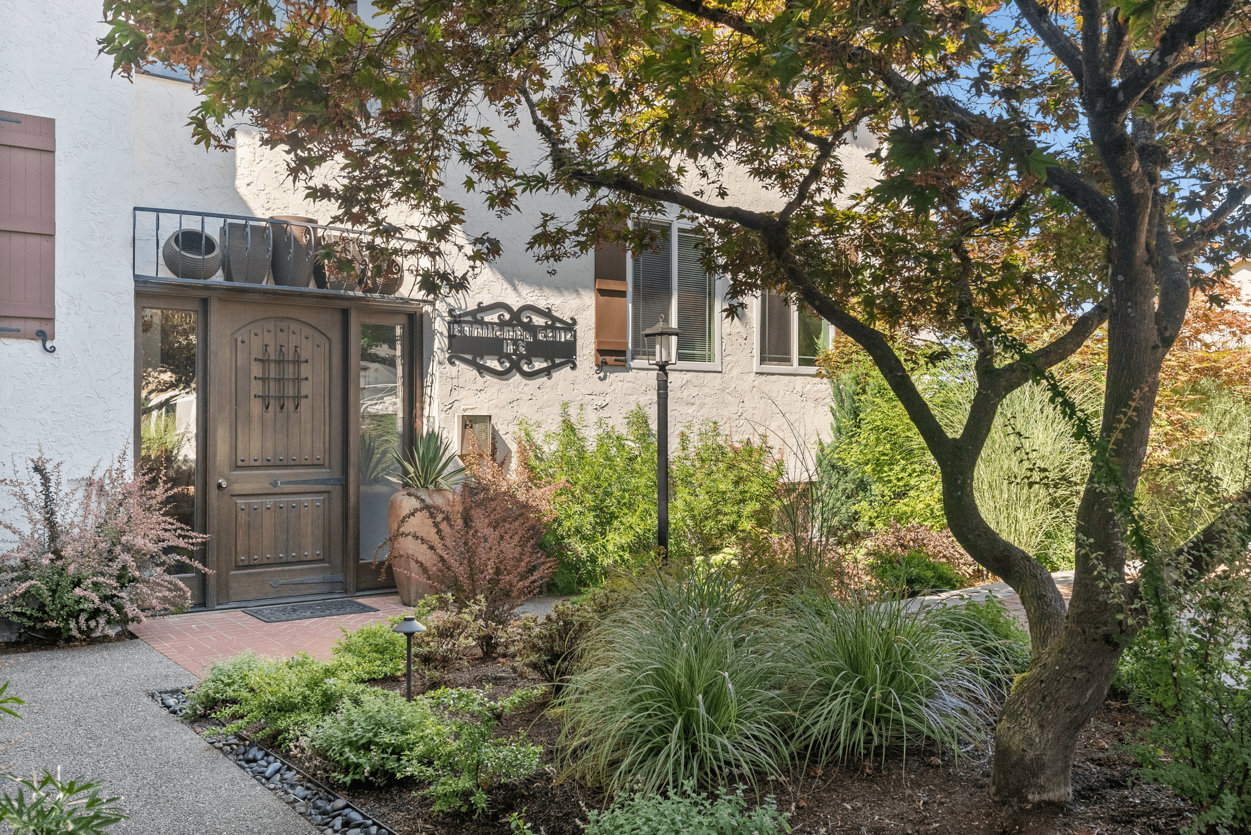 Charming entrance to a serene apartment, featuring lush greenery and a stylish wooden door, creating an inviting atmosphere.